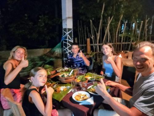a group of people sitting around a table eating food at Ancient Gardens Villa in Pinnawala