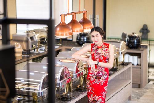 a woman in a red dress standing behind a counter at Villa Baron SHA PLUS in Nonthaburi