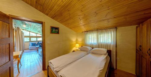 a bedroom with a large bed with a wooden ceiling at Къща за гости "Панорама" Проглед in Smolyan