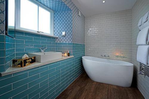 ein blau gefliestes Badezimmer mit Badewanne und Waschbecken in der Unterkunft Monks Ballyvaughan in Ballyvaughan