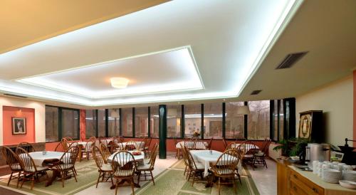 a dining room with tables and chairs and windows at Agriani Hotel - Xanthi Pool & Mountain Views in Xanthi
