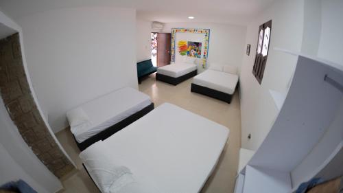 a small room with two beds and two chairs at Hostal Barrio Abajo in Barranquilla