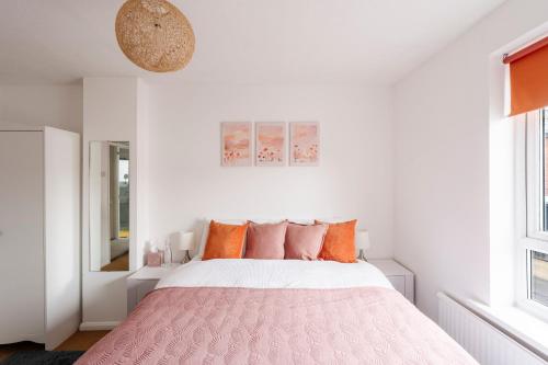 a bedroom with a pink bed with orange pillows at La Casa Bianca in Bury Saint Edmunds