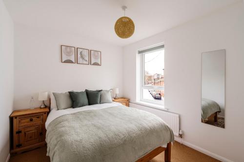 a white bedroom with a bed and a window at La Casa Bianca in Bury Saint Edmunds