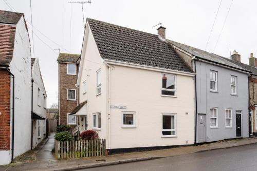 a white house with a black roof on a street at La Casa Bianca in Bury Saint Edmunds