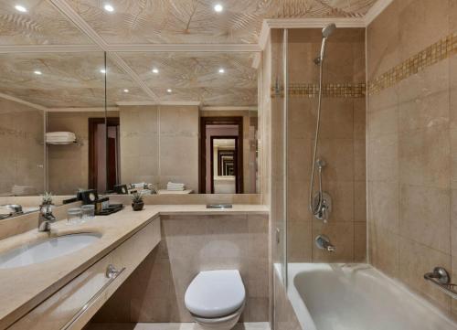 a bathroom with a tub and a toilet and a sink at The Herbert Eilat - All inclusive Plus in Eilat