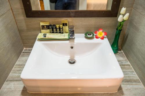 a white sink in a bathroom with a mirror and flowers at Villa Baron SHA PLUS in Nonthaburi