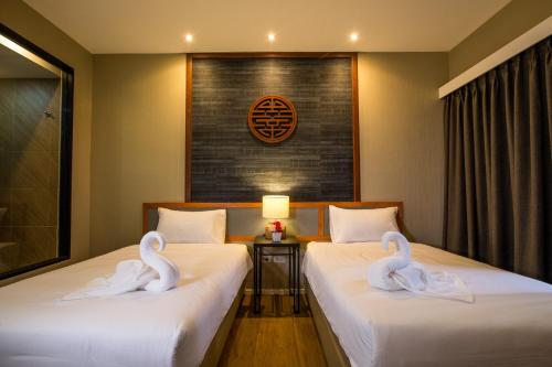 two swans sitting on two beds in a room at Villa Baron SHA PLUS in Nonthaburi