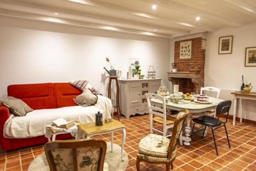 chez Thérèse في أوكسون: غرفة معيشة بها أريكة حمراء وطاولة