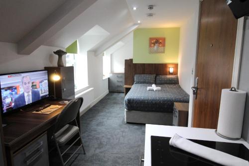 a small hotel room with a bed and a television at Victoria House - Deluxe Studios in Coventry City Centre, free parking, by COVSTAYS in Coventry