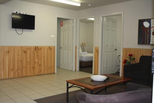 a living room with a table and a tv on the wall at Ingenia Holidays Nepean River in Emu Plains