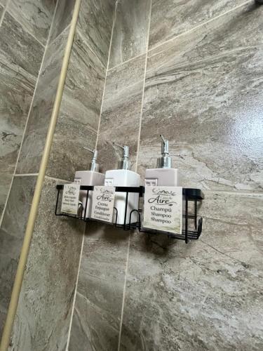 a bathroom with three soap dispensers on a wall at Casa de Aire Ezeiza in La Unión