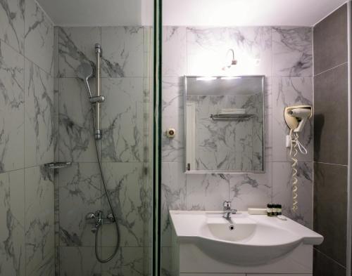 ein Badezimmer mit Dusche, Waschbecken und einer Duschkabine aus Glas in der Unterkunft Mendi Hotel in Kalandra
