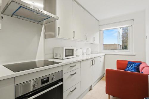 a kitchen with white cabinets and a sink and a microwave at Central London flat 10 min to Westminster in London