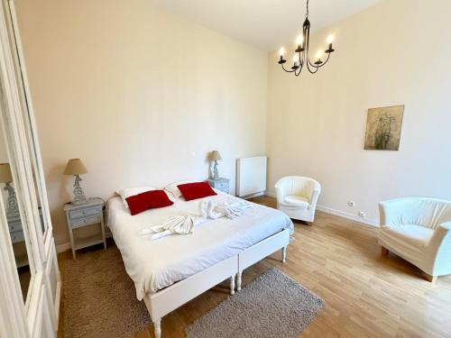 a white bedroom with a bed and a chair at Studio au cœur du château in Monchy-Humières
