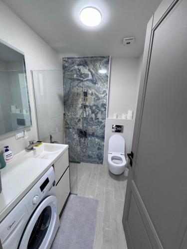a white bathroom with a toilet and a sink at Batumi in the waves in Batumi