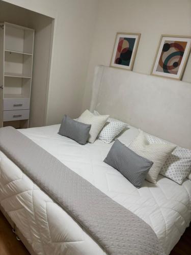 a large white bed with three pillows on it at Bello Departamento Completo con 2 recámaras! in San Baltasar