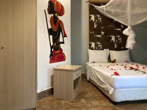 a bedroom with a bed with a painting on the wall at KC Bungalows in Nungwi