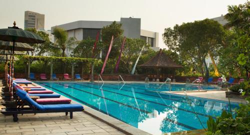 a large swimming pool with lounge chairs and an umbrella at Bumi Surabaya City Resort in Surabaya