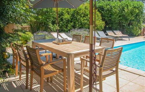 a wooden table with chairs and an umbrella next to a pool at Luxueuse Maison Avec Piscine in Cravans