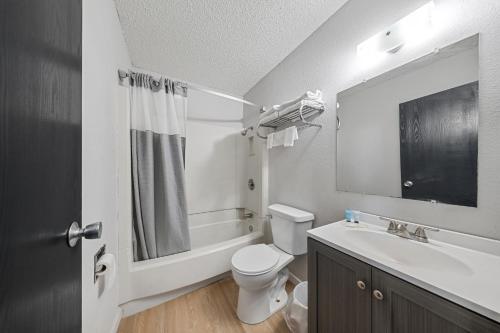 a bathroom with a toilet and a sink and a mirror at Willow Inn Suites Moorhead Fargo in Moorhead
