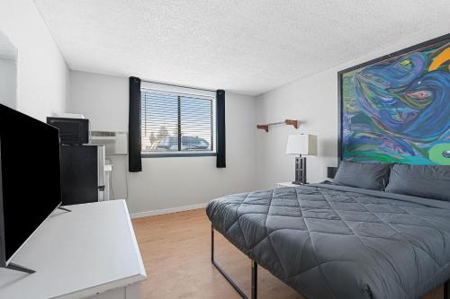 a bedroom with a bed and a painting on the wall at Willow Inn Suites Moorhead Fargo in Moorhead