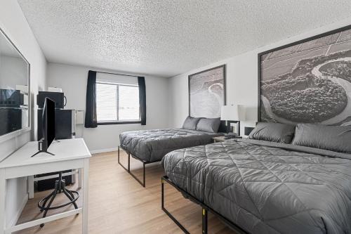 a bedroom with two beds and a flat screen tv at Willow Inn Suites Moorhead Fargo in Moorhead