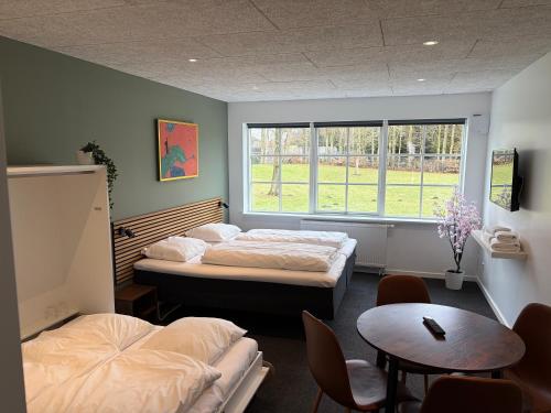 a room with two beds and a table and a window at Blommenslyst Kro in Blommenslyst