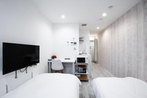 a white bedroom with two beds and a tv at Boa Sorte Hotel AD0515 in Tokyo