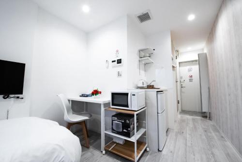 a white room with a bed and a desk with a microwave at Boa Sorte Hotel AD0515 in Tokyo