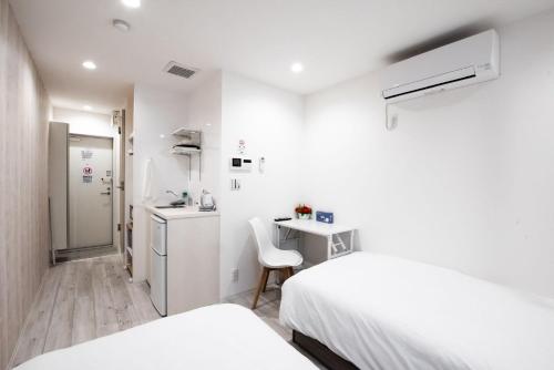 a white room with two beds and a small kitchen at Boa Sorte Hotel AD0515 in Tokyo