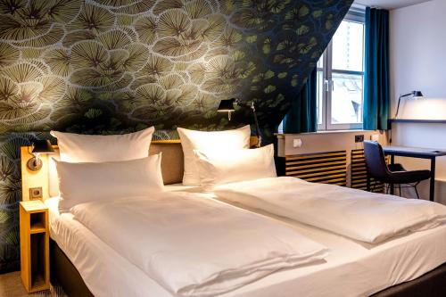 a hotel room with a large bed with white sheets at Motel One Frankfurt-Hauptbahnhof in Frankfurt