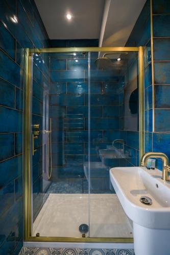 a blue tiled bathroom with a shower and a sink at Dalrigh House in Oban