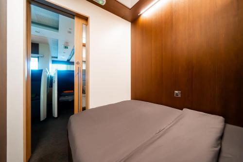 a small bedroom with a bed and a wooden door at Sleepover Terminal 3, Concourse A - formerly sleep 'n fly in Dubai