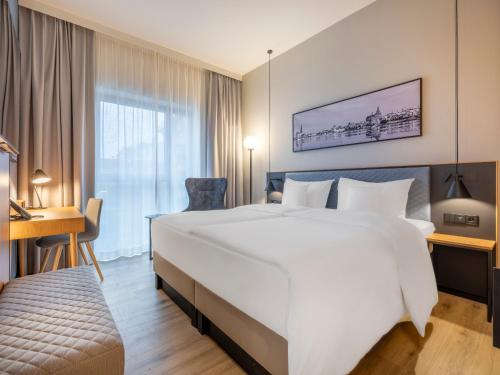 a hotel room with a large white bed and a desk at ScanHotels Stadthafen in Rostock