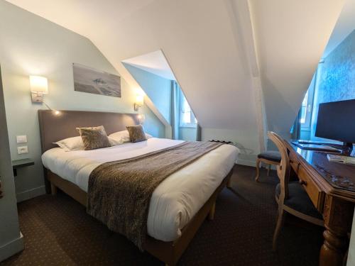 a bedroom with a bed and a desk with a computer at Hotel des Abers in Saint Malo