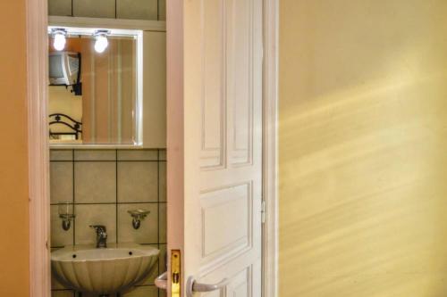 a bathroom with a sink and a mirror and a door at Mainades Maisonettes & Studios - Andros Serene Escape in Ménites