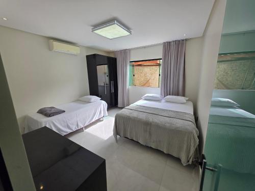 a hotel room with two beds and a window at Inocoop house in Camaçari