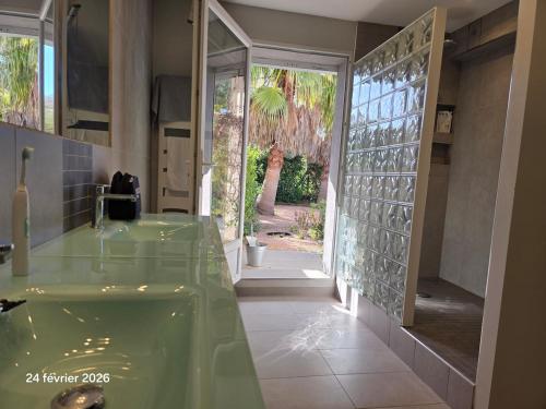 a bathroom with a green tub and a sliding glass door at Spacieuse villa au calme avec grande piscine in Bormes-les-Mimosas