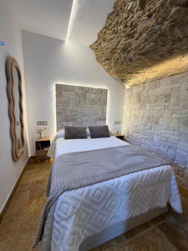 a bedroom with a large bed in a stone wall at Casa Cueva Transmina 10 in Setenil