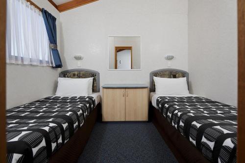 a room with two beds and a table and a mirror at Ingenia Holidays Nepean River in Emu Plains