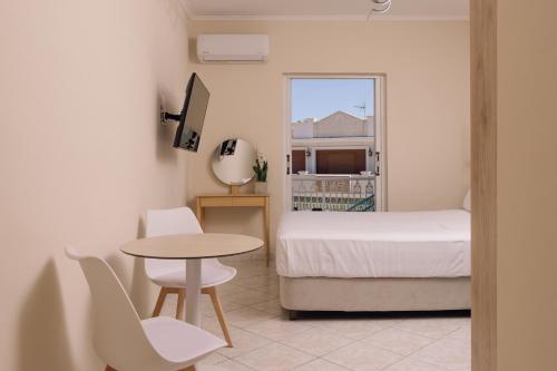 a bedroom with a bed and a table and a table and chair at Maroudas Apartments in Planos