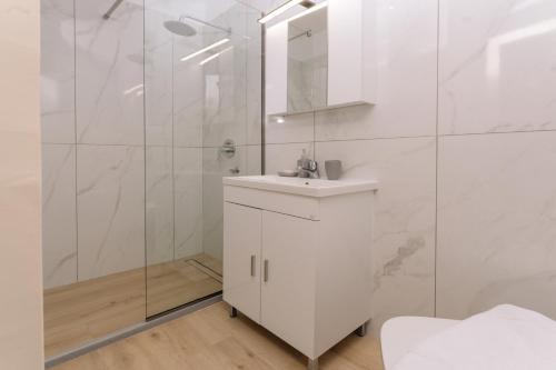 a white bathroom with a sink and a shower at Maroudas Apartments in Planos
