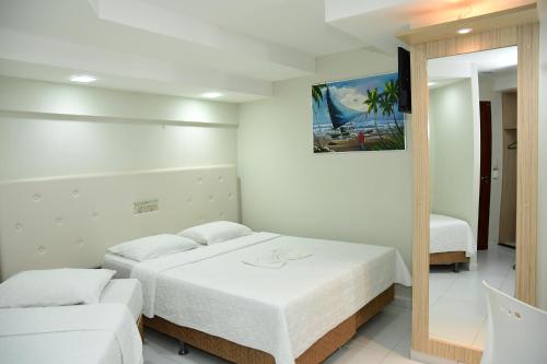 a white bedroom with two beds and a mirror at Hotel Serrano Martins in Martins