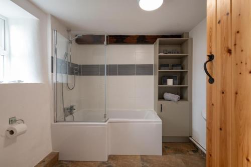 a white bathroom with a tub and a shower at Bryn Lon in Caeʼr-geiliog