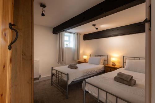 a bedroom with two beds and a window at Bryn Lon in Caeʼr-geiliog