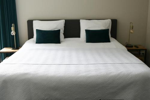 a large white bed with two blue pillows on it at B & B Meet the Dutch in Ridderkerk