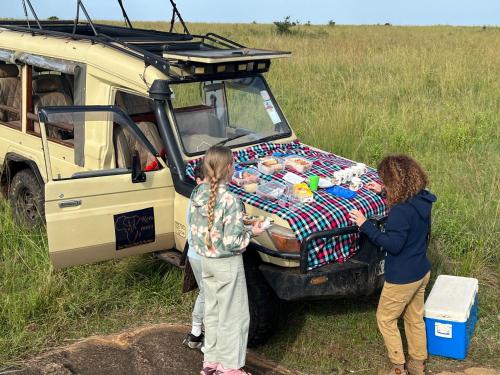 two women standing in front of a vehicle with a table at Escape Haven Mara in Masai Mara