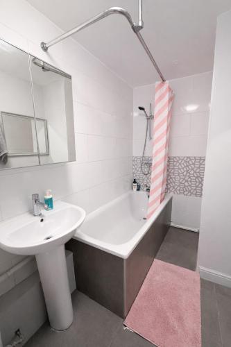 a white bathroom with a sink and a bath tub at Spacious Double Room in Shared Flat in Sutton