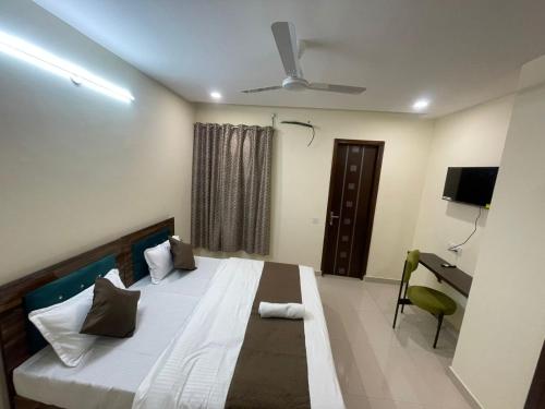 a bedroom with a bed and a desk and a television at Cozy Inn Hotel in Noida